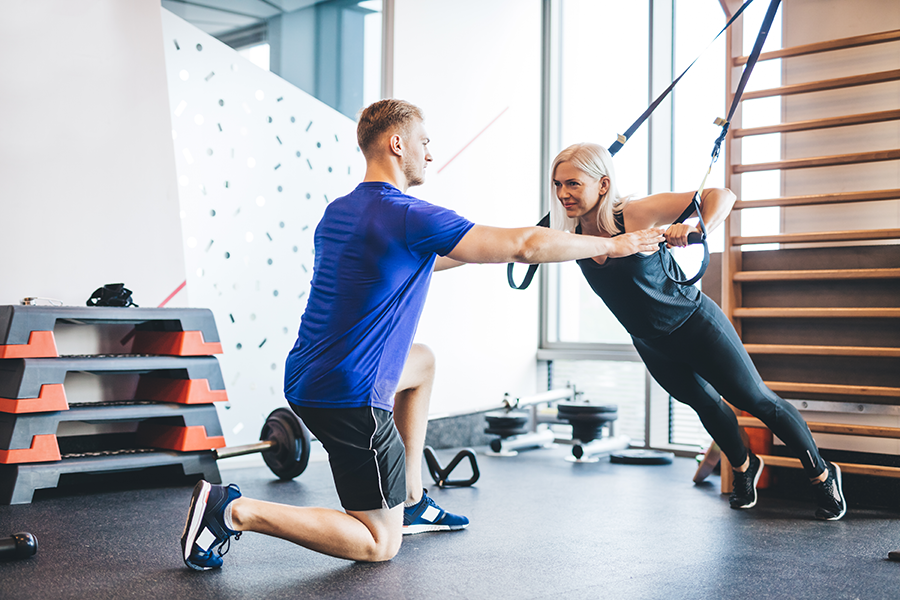 woman-exercising-with-personal-trainer-at-the-gym