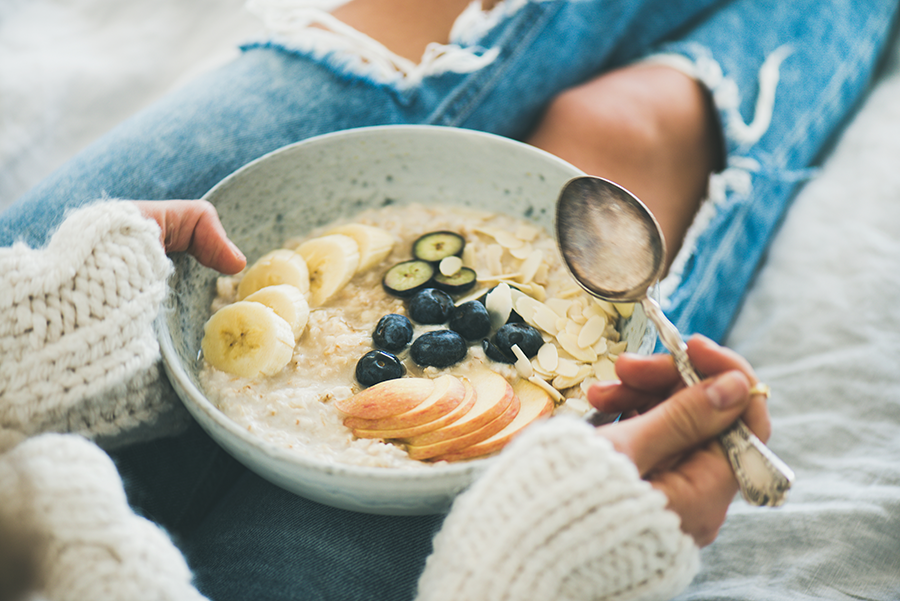 woman-in-jeans-and-sweater-eating-healthy-oatmeal-healthy eating